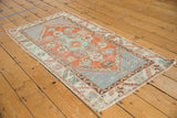 Distressed vintage Oushak runner corner showing worn brick red, slate blue, and serrated leaf border.