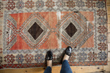Distressed vintage Oushak rug showing exposed foundation, pale brick red, and ivory patterns.