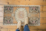 Faded burnt orange and antique ivory germinating plant motif on distressed vintage Oushak rug.
