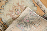 Folded Oushak rug corner revealing distressed pile, muted geometric patterns, and hand-knotted foundation.