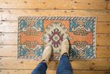 Hand-knotted vintage Oushak rug displaying distressed terra cotta, ivory, aqua, and burgundy medallion.