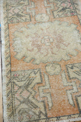 Textural detail of the faded burnt orange and ivory knot heads on a distressed Oushak rug mat.