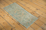 Traditional distressed Oushak rug mat, showing faded medallion and soft green palette.
