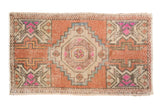Vintage distressed Oushak rug featuring a stepped geometric medallion, brick red, ivory, and fuchsia.