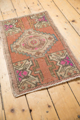 Worn pile of a distressed Oushak rug, showing dusty rose, ivory, and fuchsia patterns.