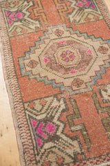 Geometric pattern detail with fuchsia, dusty rose, and ivory tones on distressed Oushak rug.