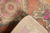 Vintage Distressed Oushak rug folded, revealing hand-knotted reverse and fuchsia geometric pattern.