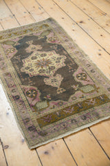 Ornate distressed Oushak rug runner with soft mauve, ivory, charcoal, and pinwheel floral motifs.