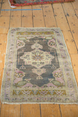 Distressed Oushak rug corner with visible pinwheel motif, soft mauve and bronze tones.