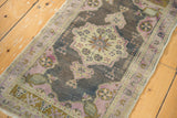 Distressed Oushak runner corner showing mauve, bronze, and ivory pinwheel pattern.