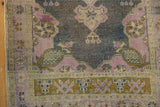 Distressed vintage Oushak rug runner showing faded mauve, dark navy field, and bronze geometric border.