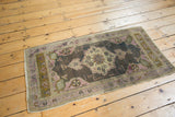 Distressed Oushak rug runner's fringed corner with mauve pinwheel and bronze elements.
