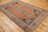 Distressed vintage Oushak rug corner showing terra cotta and royal blue geometric palmettes.
