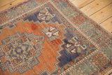 Distressed Oushak rug corner, terra cotta field with royal blue geometric palmettes.
