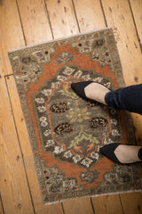 Distressed vintage Oushak rug mat showing worn pile and foundation, with pale rust and ivory florals.