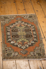 Distressed Oushak rug corner with visible wear, short fringe, and muted floral motifs.