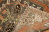 Distressed Oushak rug pile with pale rust floral motif, worn to show foundation and fringe.