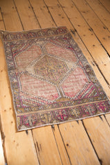 Distressed vintage Oushak rug corner, showing mauve, aubergine, and ivory geometric border.