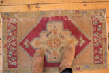 Upper left corner of distressed Oushak rug, showing worn green border and cherry red medallion.