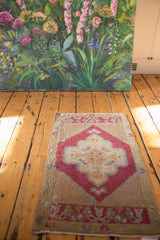 Distressed Oushak rug mat with cherry red scalloped medallion and worn sand-beige field.