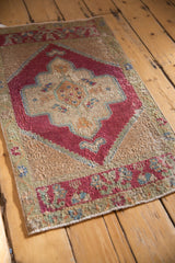 Vintage distressed Oushak rug mat corner, showing worn cherry red and sand pile with blue-green accents.