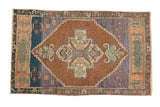 Hand knotted distressed vintage Oushak rug with chocolate medallion and aqua corner overlays.