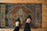 Distressed Oushak rug close-up: medallion, serrated corner overlay, chocolate, royal blue, aqua tones.