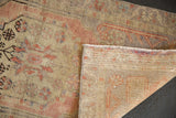 Folded corner of distressed Oushak rug, blush florals with mostly even wear and visible foundation weave.