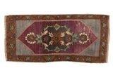 Distressed Oushak rug mat with an aubergine Rococo medallion, oversized floral palmette finials, and slate blue field.
