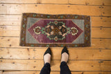 Distressed Oushak rug mat showcasing aubergine Rococo medallion, slate blue field, and even wear.