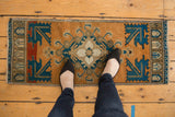 Distressed corner of a vintage Oushak rug, showing serrated geometric navy blue and pale rust forms.