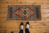 Vintage distressed Oushak rug corner, aubergine border with pinwheel motifs, softened silver field.