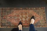 Distressed Oushak rug with faded mauve geometric medallion, slate blue border, and visible foundation wear.