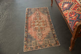 Vintage distressed Oushak rug showcasing geometric pinwheel, pomegranate motifs, dusty mauve and slate.