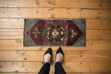 Distressed Oushak rug mat, showing worn texture and Rococo floral medallion in deep, muted tones.