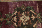 Distressed aubergine Oushak rug showing low pile texture and Rococo palmette motif.