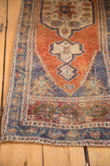 Distressed Oushak rug end displays germinating plant motifs, terra cotta, dusty blue, and worn pile.