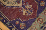 Distressed Oushak rug with aubergine field, geometric sea foam border, and even wear.