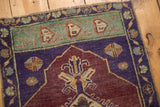 Vintage distressed Oushak rug section with aubergine field, mint geometric, and violet floral border.