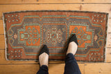 Distressed Oushak rug with central triple medallion, rust orange, sea foam, and even wear.