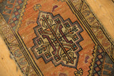 Distressed vintage Oushak rug border with tangerine, dusty gold, charcoal geometric motifs.