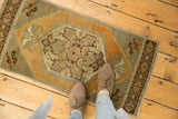 Distressed vintage Oushak rug's central floral medallion with faded orange, bronze, and ivory tones.