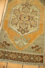 Distressed Oushak mat's lower section: pale orange border, floral palmette, and worn pile.