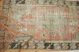Vintage distressed Oushak rug, showing faded blush and seafoam florals with a dark geometric border.