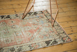 Faded blush, seafoam, and charcoal tones in the pinwheel corner of the distressed Oushak runner.