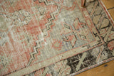 Distressed Oushak runner corner with faded blush, seafoam, and charcoal geometric spandrel.