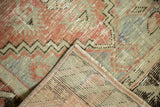 Folded corner of vintage Oushak rug, revealing hand-knotted foundation and distressed pile.