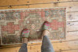 Vintage distressed Oushak rug mat with worn texture, dusty rose, grey, and ivory hues.