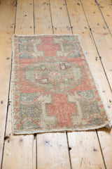 Distressed Oushak rug corner displaying even wear, textured pile, and dusty rose hues.