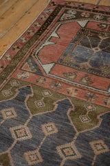 Distressed Oushak rug texture with primitive geometric motifs in muted blush, blue, and bronze.
